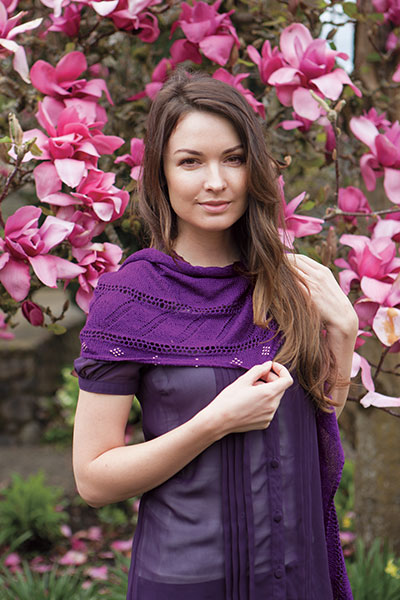 Model wearing the Kinross Avenue Wrap in front of a tree covered in pink flowers.