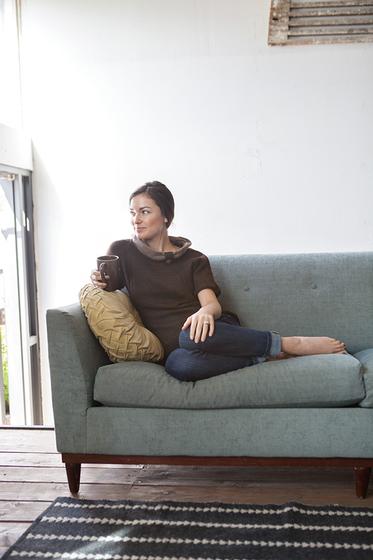 Woman wearing the Jayashri Pullover while reclining on couch.