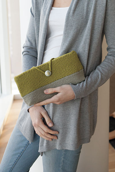 Model holding a yellow and gray version of the Althea Clutch bag