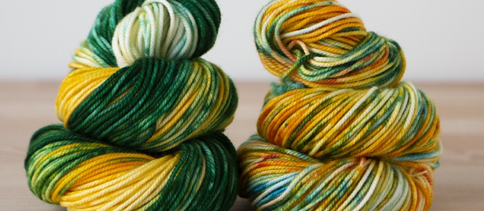 Closeup of yarns dyed with greens, yellows, and oranges.