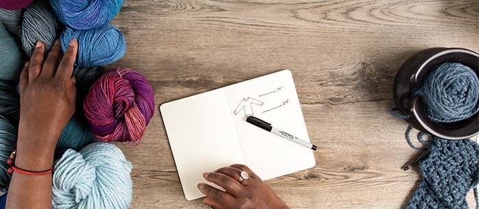 A notebook sitting on a table surrounded by various yarns