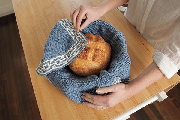 Quilted insulated bread cloth wrapped around a loaf of bread in a basket