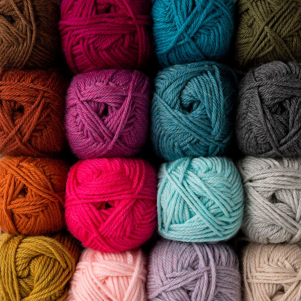 a photo of many skeins of Swish Worsted yarn in different colorsstacked on top