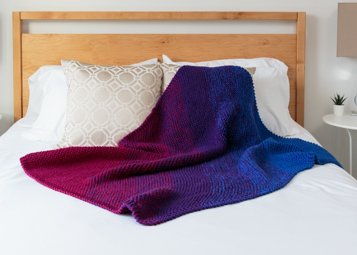 Continuation Blanket: A knitted blanket with a diagonal gradient going from maroon to purple to blue.