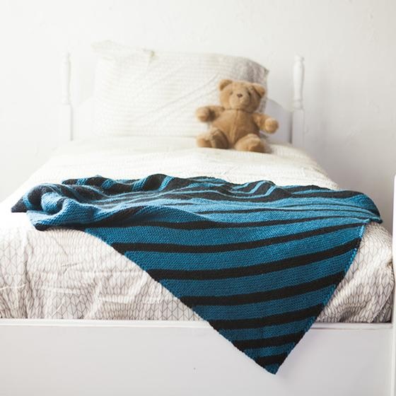 A blue knitted blanket with diagonal stripes of blue and black.