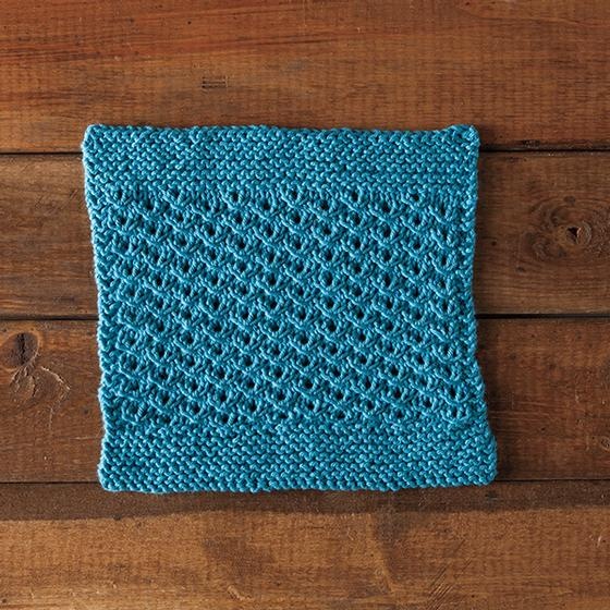 Sunny Days Dishcloth: A blue knitted dishcloth with a garter stitch border and a lace-like middle